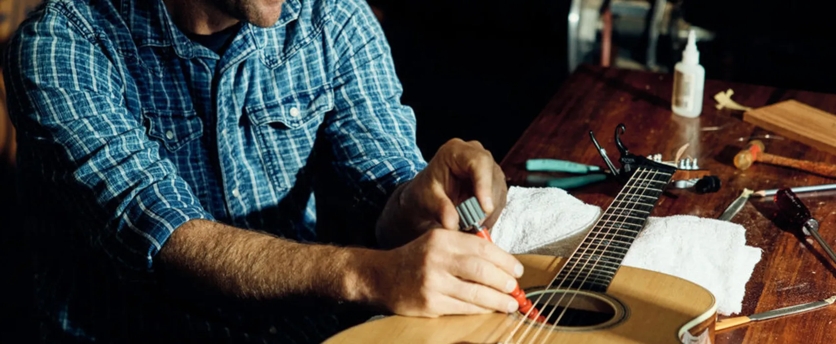 Image of Andy Powers adjusting a Taylor acoustic guitar with an Action Control Neck
